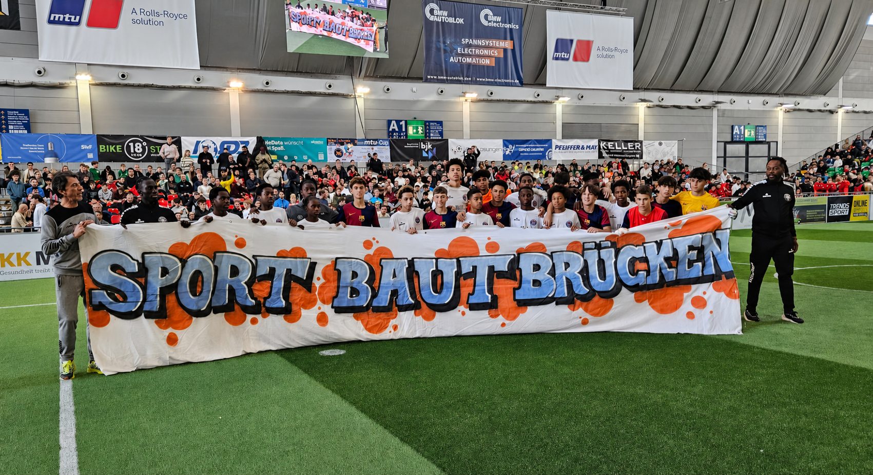 Jugendliche mit dem Banner „Sport baut Brücken“ beim MTU Cup
